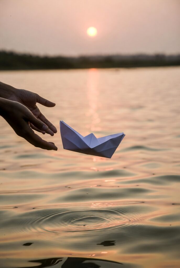  mãos soltando barco de papel na água representando transformação e cura do estilo de apego