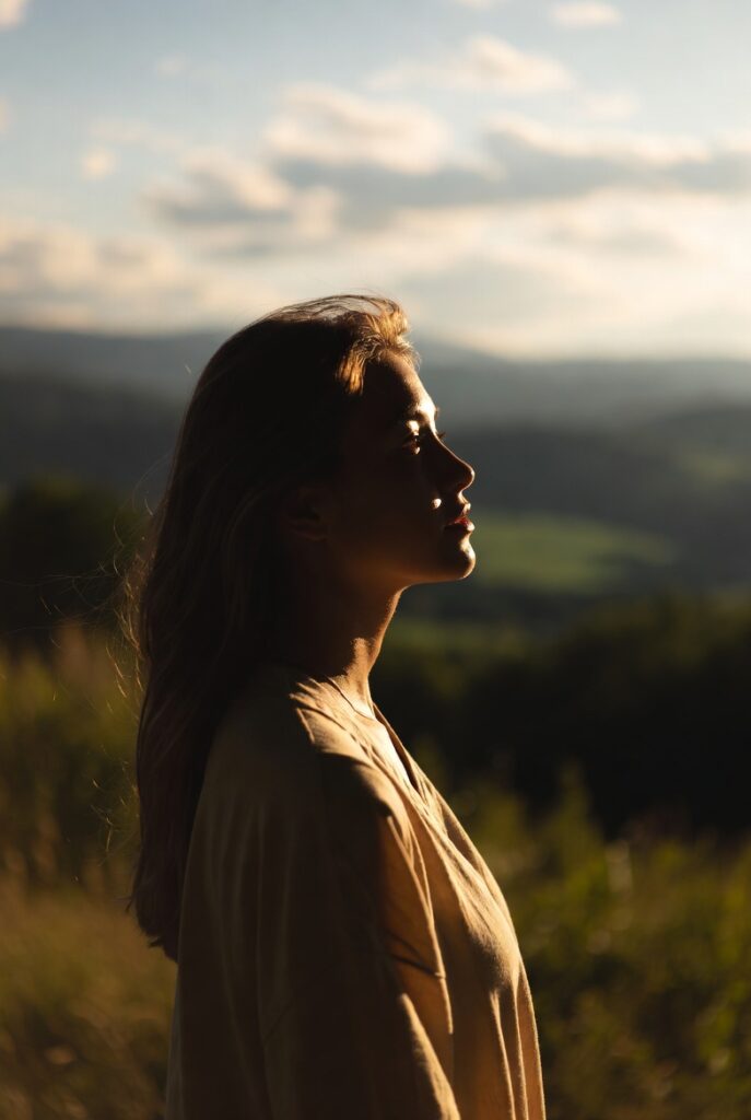 Mulher olhando para o horizonte com serenidade representando a clareza que vem depois de reconhecer os sinais da alma esta pedindo uma mudança