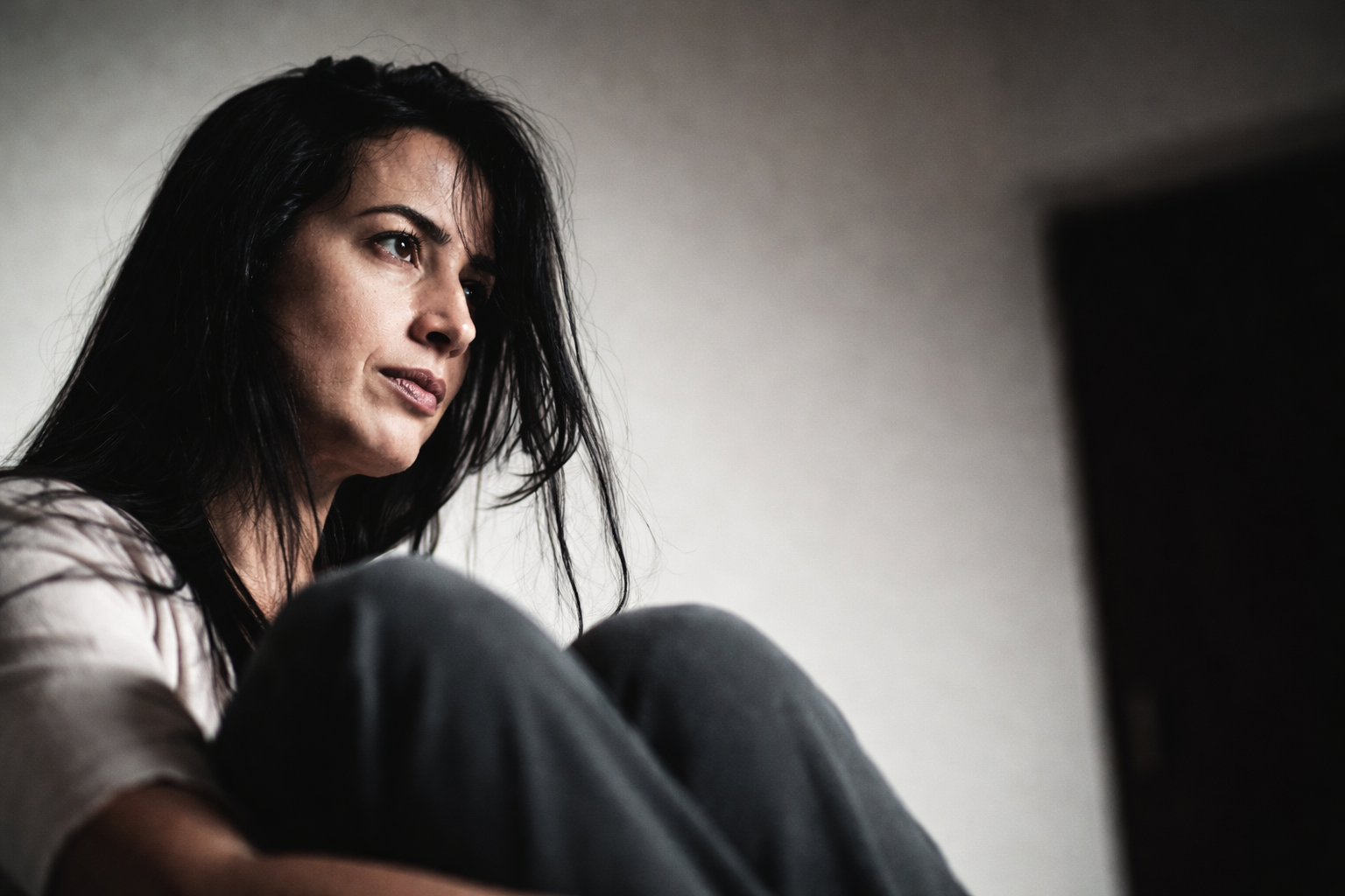 Mulher sentada com olhar distante representando o cansaço existencial e o esgotamento silencioso da identidade em transição