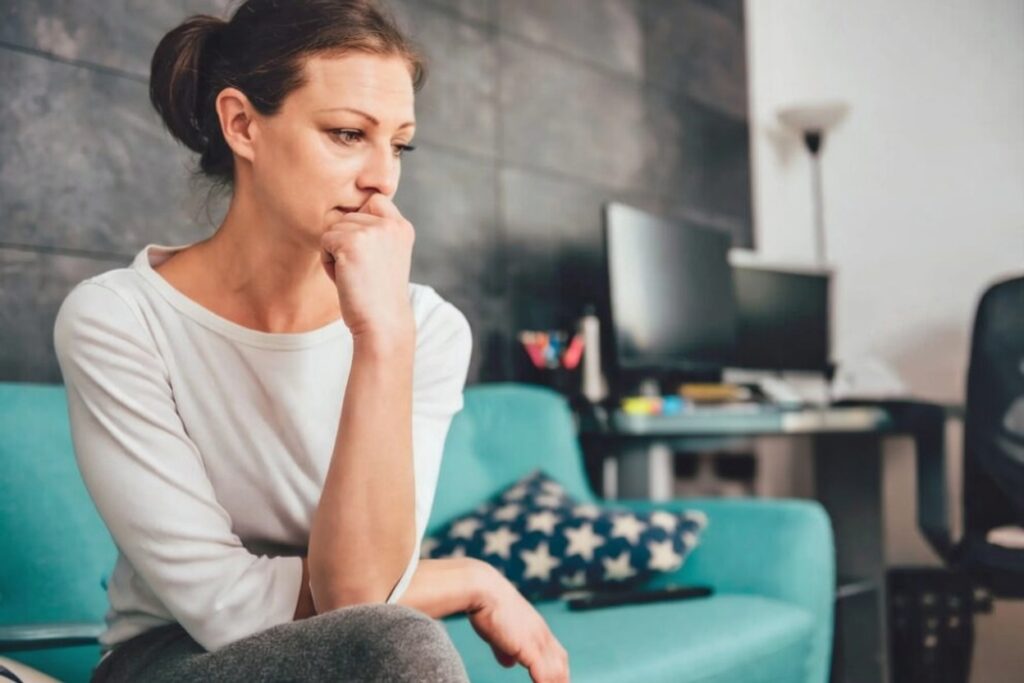 Mulher cansada sentada sozinha representando o esgotamento de sempre ser a pessoa forte