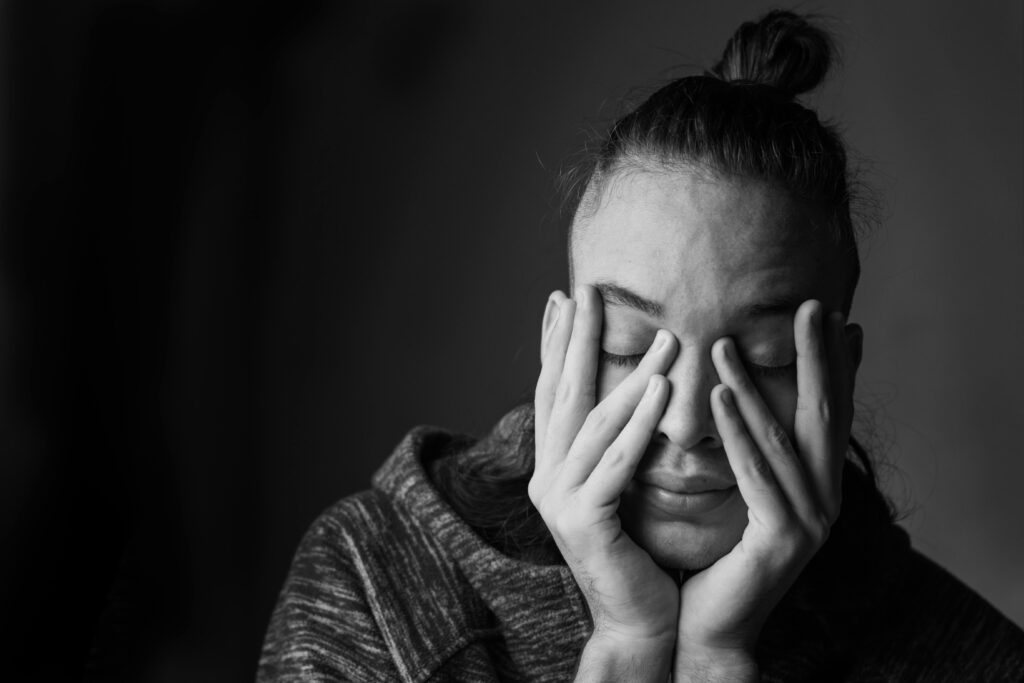 Pessoa com expressão de frustração ou tensão tentando se concentrar, representando a dificuldade de parar de pensar durante a meditação