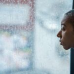 Pessoa olhando pela janela com expressão distante representando a dissociação emocional