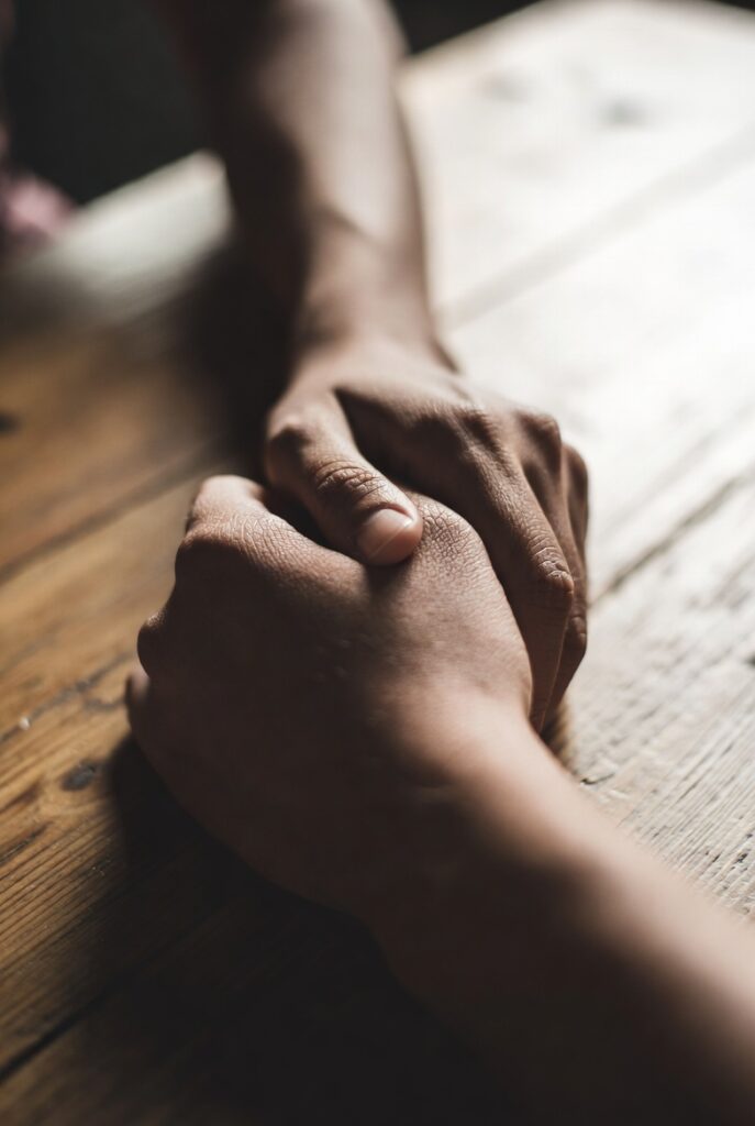 Mãos adultas em gesto de cuidado representando a prática de regulação emocional e autoconhecimento