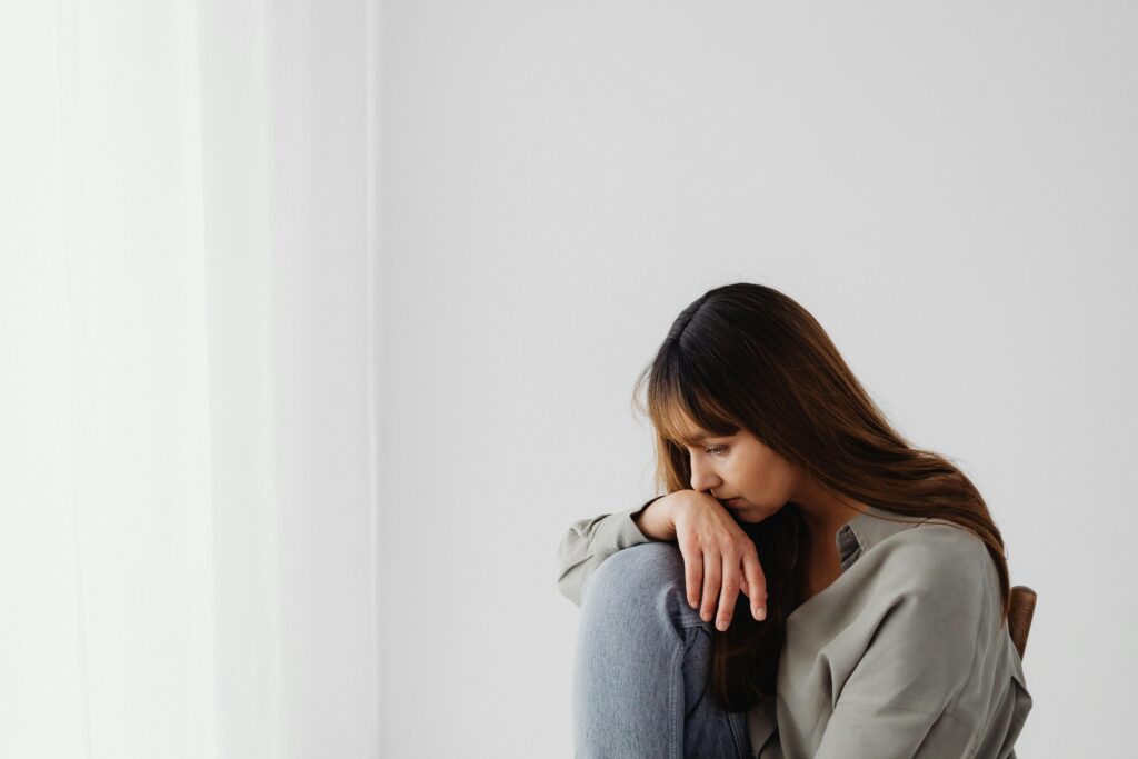 Mulher sozinha com expressão de peso interior e olhar distante representando o sofrimento silencioso de um relacionamento que faz mal